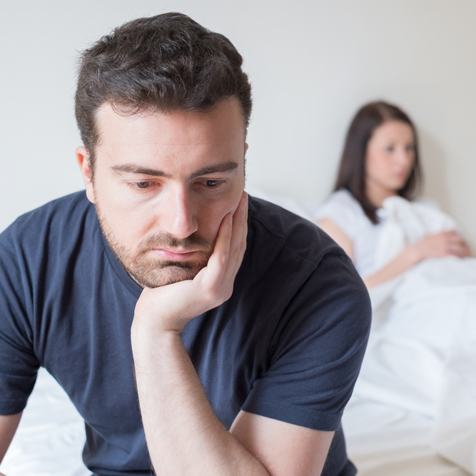 man sitting at the end of the bed looking disdained.