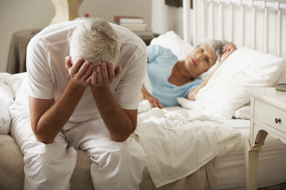 Worried Senior Man Sits On Bed