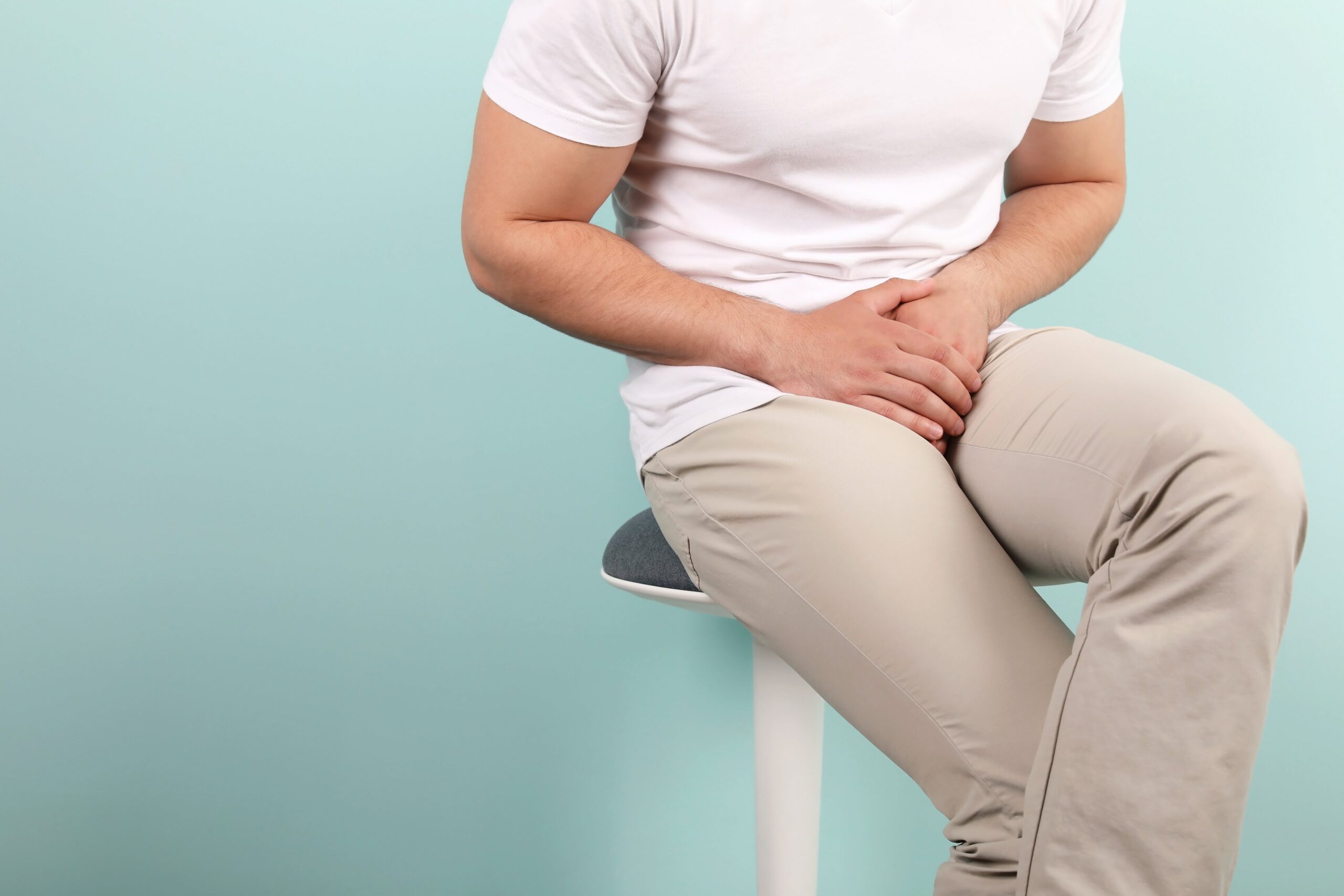 man sitting holding his bladder.